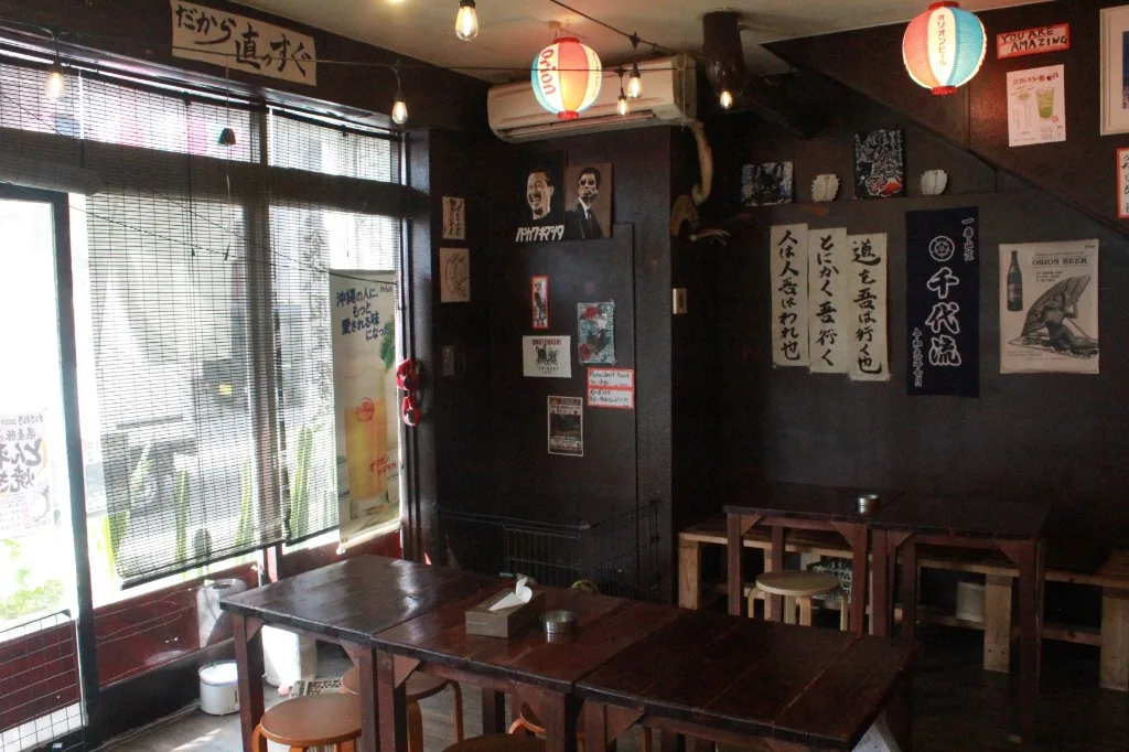 木のテーブル席と、書と提灯の並ぶ店内。席に鉄板はない